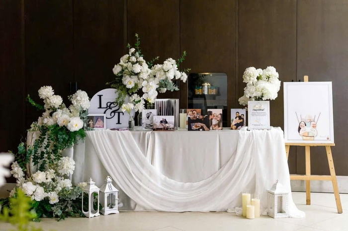 Bàn gallery phủ voan trắng, hoa tươi và ảnh cưới